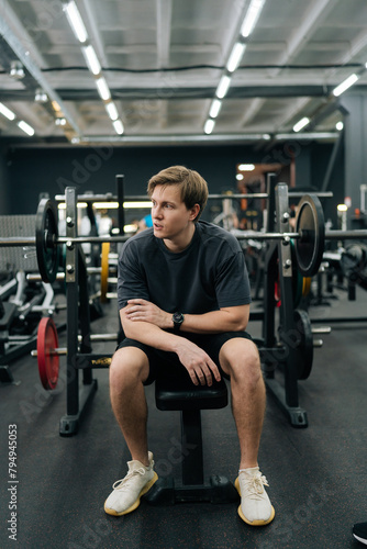 Vertical portrait of beginner sportsman having accident injury and hurt at arms while workout and weight training at gym. Athletic man suffering from muscle injury while exercising at sport club.