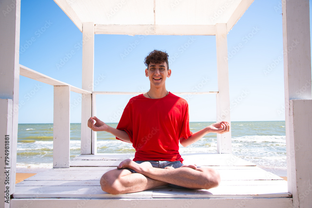 A young attractive man meditates by the sea. A young attractive man meditates by the sea.