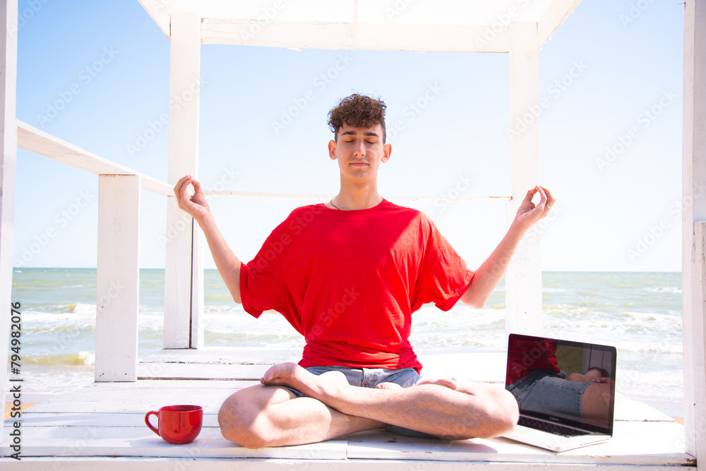 A young attractive man meditates by the sea. A young attractive man meditates by the sea.