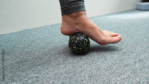 Massaging foot with a relaxing roll. Woman massaging foot with massage ball. Myofascial relaxation of foot muscles. Preventing foot fatigue