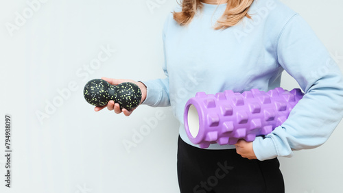 Woman holding massage rollers for myofascial release in her hands. Fitness trainer with items for myofascial release.