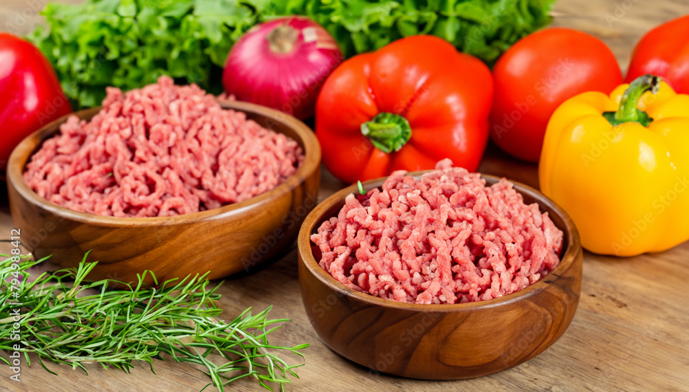 Fresh minced meat in a wooden plate for cooking and condiments. Vegetables on a wooden background
Fresh minced meat in a wooden plate for cooking and condiments. Vegetables on a wooden background
