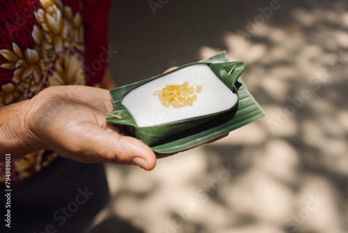 A hand presenting a Thai dessert made with tapioca pearls on banana leaf, indicative of Thai cuisine, suitable for cultural festivals like Songkran or Loy Krathong.