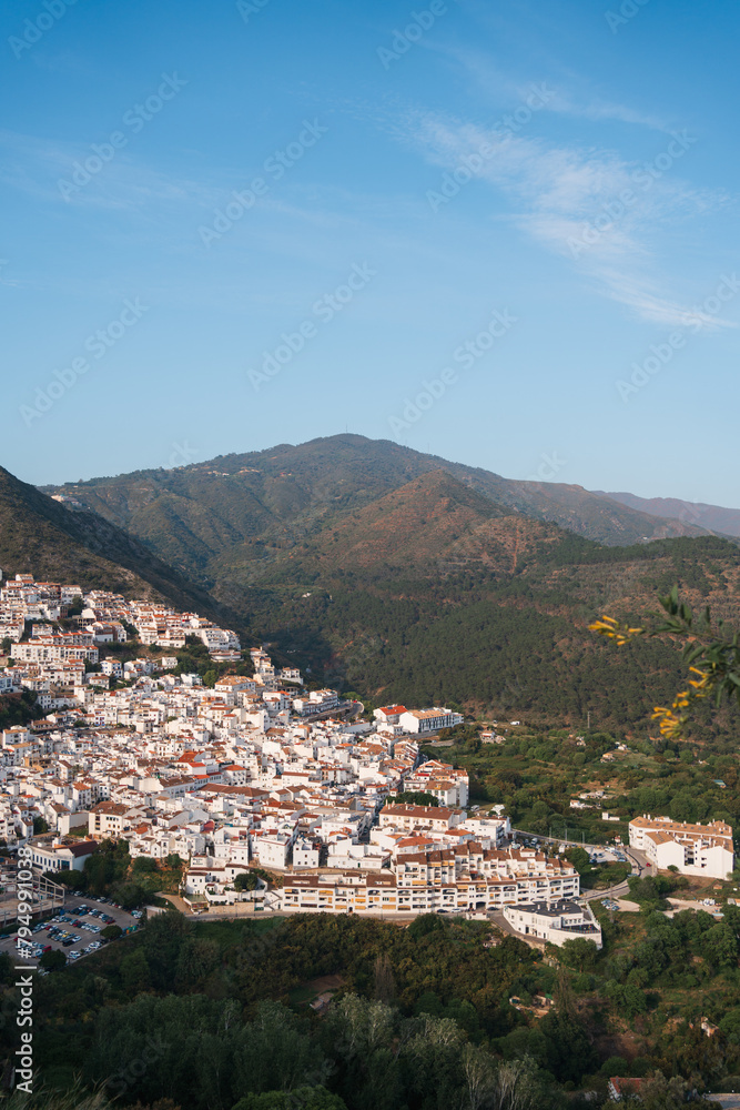 Drone shot over Ojen, Spain showcasing the white buildings nestled in the green hills of Andalusia