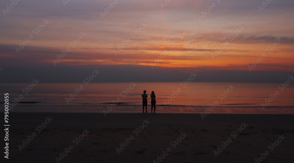 silhouette of The couple standing at the Beach looking Sunrise at the beach of Thailand