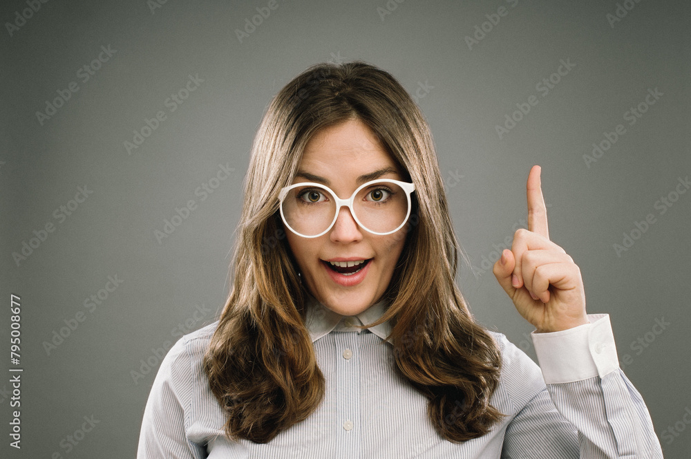 Glasses, idea and portrait of girl nerd in studio on gray background for accessories or fashion. Aha, finger and inspiration cute geek or natural person in eyewear for retro or vintage style Glasses, idea and portrait of girl nerd in studio on gray background for accessories or fashion. Aha, finger and inspiration cute geek or natural person in eyewear for retro or vintage style