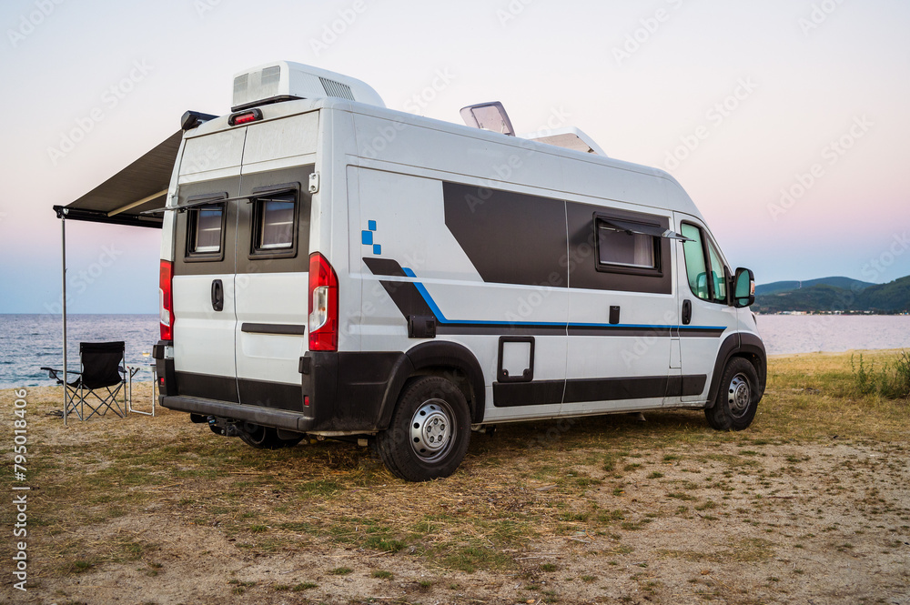 Campervan or motorhome parked on the beach in Greece. Rv campervan is wild camping on the beach in Greece, Albania or Croatia in the evening.