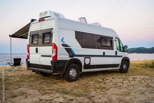 Campervan or motorhome parked on the beach in Greece. Rv campervan is wild camping on the beach in Greece, Albania or Croatia in the evening. © _jure