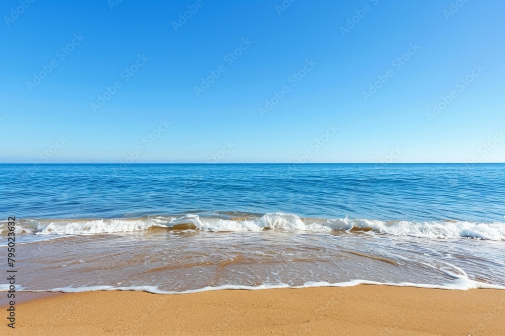 A beach with soft golden sand and gentle waves under a clear blue sky.