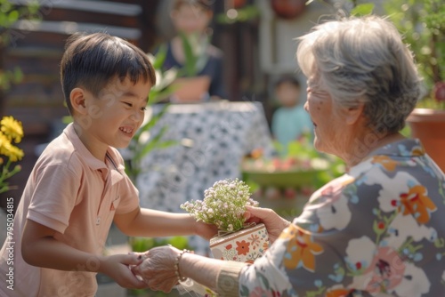 In a warm outdoor setting, a child lovingly gives a potted plant to a senior woman, symbolizing the tender exchange of care and affection photo