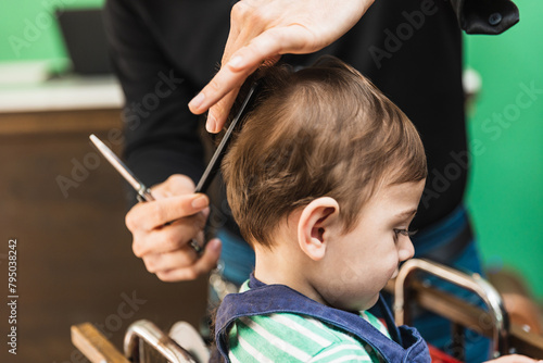 A toddler is getting a new hairstyle at the barbers salon