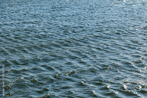 visuale in primo piano, leggermente dall'alto, di una superficie acquatica color azzurro di un fiume, increspata da piccole onde, di giorno