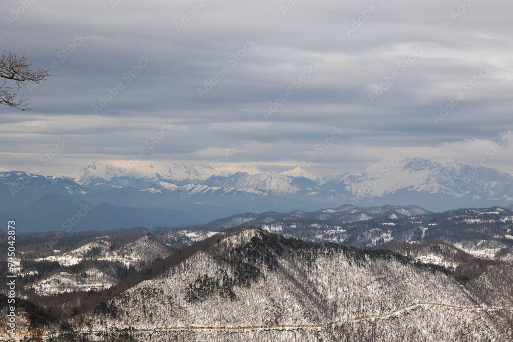 visuale dettagliata, dalla cima di un monte, di una vasta catena di montagne che si estende dalla Slovenia alle Alpi italiane, in un panorama completamente innevato, in inverno, di giorno