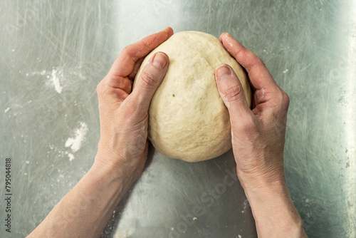 Dough in baker's hands on the background of a cutting table