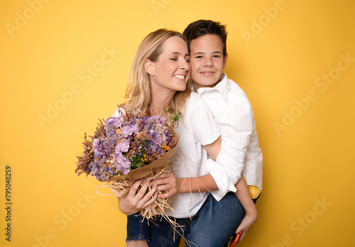 The boy gives his mother flowers and makes a surprise. Mother's day, congratulations on international women's day.