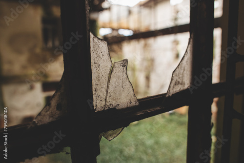 vista in primo piano di alcuni pezzi di vetro rotti di una vecchia finestra all'interno di un edificio abbandonato, nella penombra photo