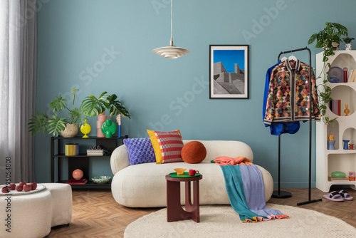 Modern and colorful interior of living room with design boucle sofa, mock up poster, shelf, plants, decorations and personal stuff. Home decor. © FollowTheFlow
