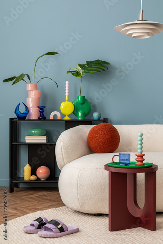 Stylish interior of colorful living room with design white sofa, black shelf with vases, book and personal accessories. Modern home decor. Template.