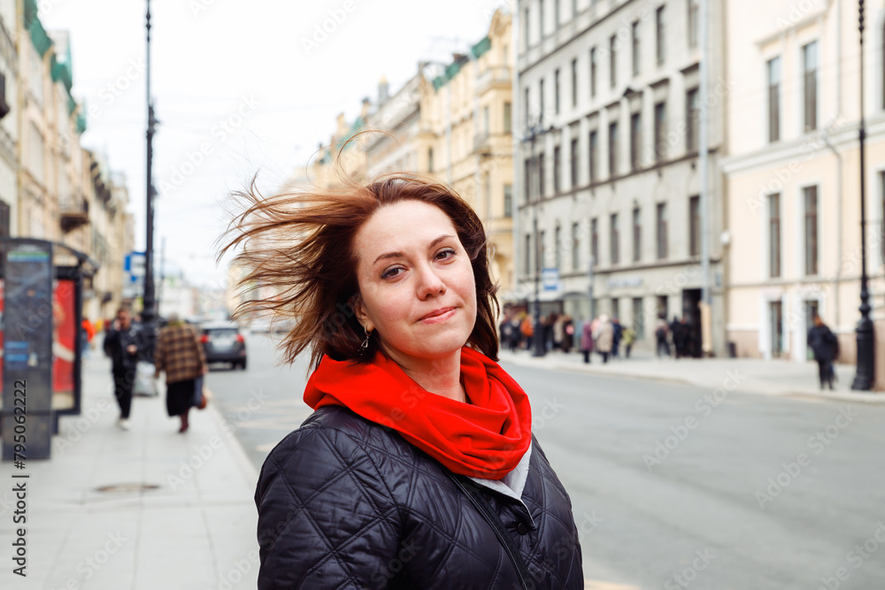 Fototapeta premium melancholy sad pensive young caucasian female woman with flowing hair looking at camera on street of european city. mental health concept. lifestyle portrait