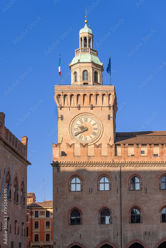 Sunlight bathes the medieval clock tower of the Palazzo d'Accursio in Bologna, highlighting its architectural grandeur and timeless presence