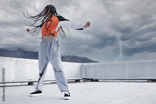 Girl, dance and hip hop outdoor on city rooftop with lightning storm and cool gen z streetwear fashion. Woman, moving and dancer with creative energy on apartment balcony and urban style or freedom