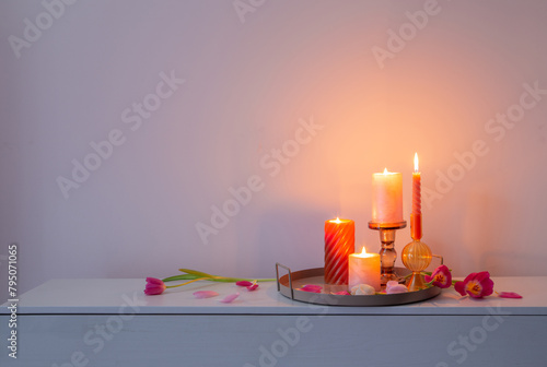 pink tulips   and burning candles  on tray on background wall