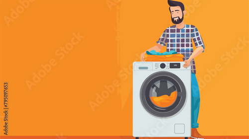 Young man with laundry near washing machine on orange