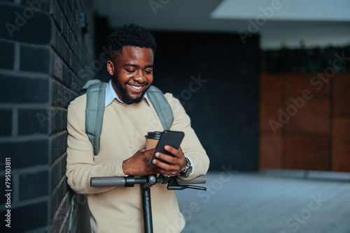 Man smiling using phone leaning on wall (ID: 795103811)