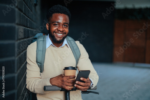 Happy man engaging with phone against dark wall (ID: 795103820)