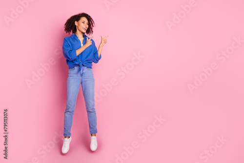 Photo of positive cheerful girl wear stylish blue clothes jump up introduce empty space isolated on pink color background