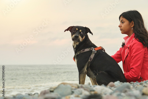 A woman sits on the beach with her dog. Summer time. Selective focus.