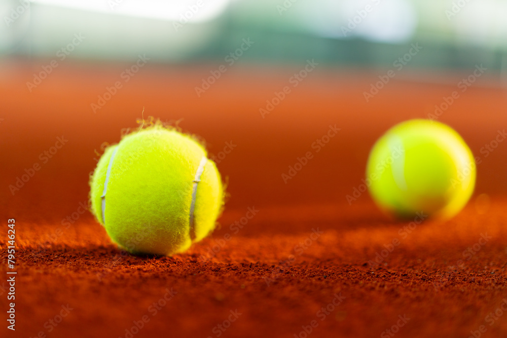 new tennis balls on orange clay court with light from right