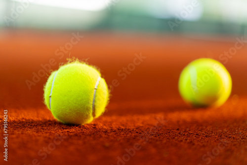 new tennis balls on orange clay court with light from right