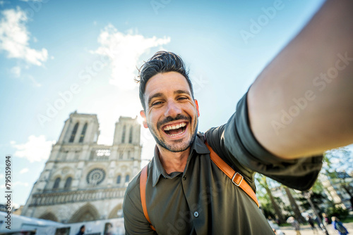 Handsome man taking selfie with smart mobile phone device on city street - Happy tourist visiting Notre Dame in Paris, France - Summer holidays and travel influencer concept