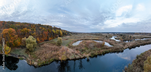 Aerial autumnal river valley panorama with autumn forest and scenic clouds in Ukraine