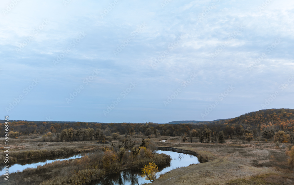 Autumn river valley with bare trees and cloudy evening sky in rural Ukraine