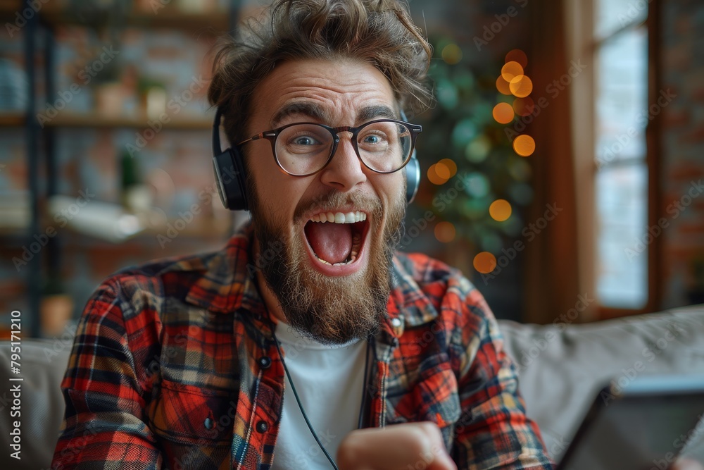 Energetic young male rejoicing while looking at a tablet, wearing a headset as if celebrating good news Energetic young male rejoicing while looking at a tablet, wearing a headset as if celebrating good news