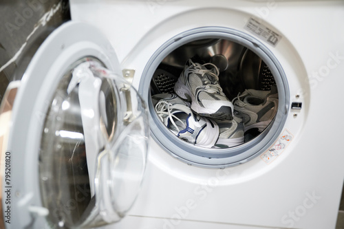 Two pairs of sneakers in washing machine. Dirty shoes need to be washed after exercising outside.