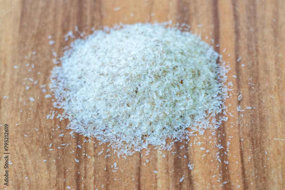 Psyllium husk isolated on wooden background. It's a common home remedy for constipation and other health issues. The husk of the Plantago ovata plant is also known as ispaghula husk, or isabgol husk Psyllium husk isolated on wooden background. It's a common home remedy for constipation and other health issues. The husk of the Plantago ovata plant is also known as ispaghula husk, or isabgol husk