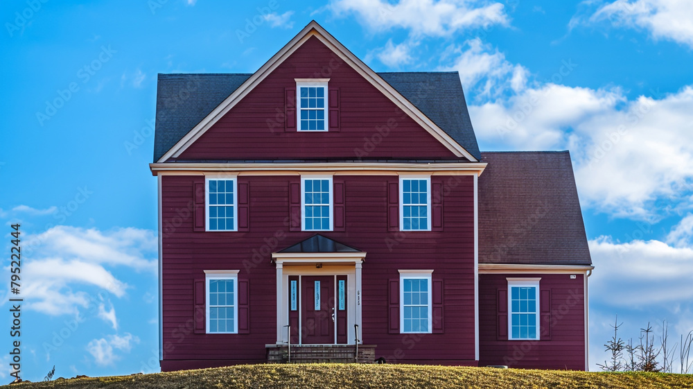 From a hilltop viewpoint, a radiant maroon house with traditional windows and shutters stands tall on a spacious lot, offering a picturesque scene against the vibrant blue sky in the suburbs. From a hilltop viewpoint, a radiant maroon house with traditional windows and shutters stands tall on a spacious lot, offering a picturesque scene against the vibrant blue sky in the suburbs.
