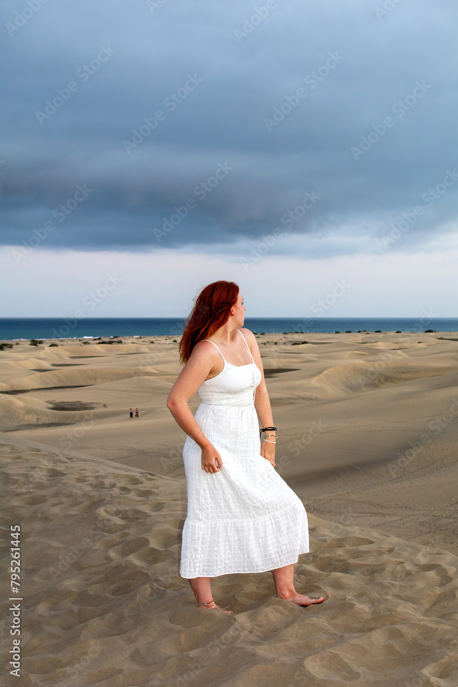 Young woman stands in the sand dunes Young woman stands in the sand dunes