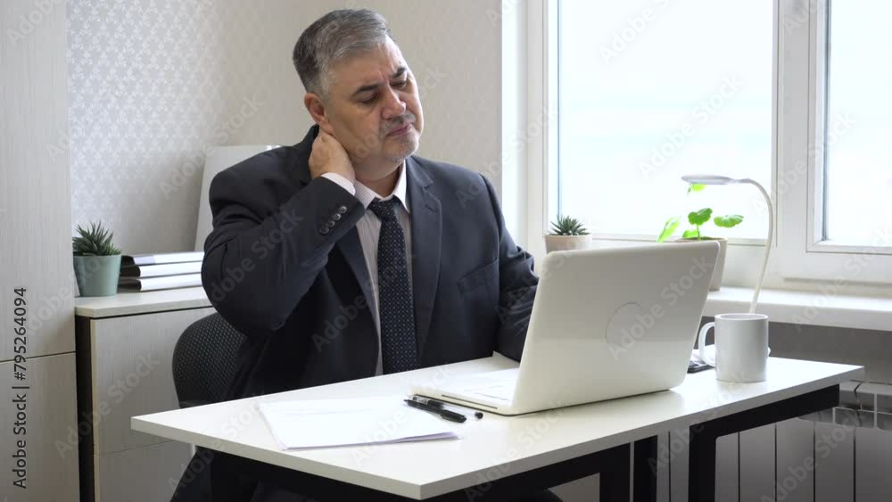A man working in an office has a sore neck due to working at the computer for a long time. Suitable for content related to office ergonomics, workplace injury prevention, and staying healthy at work. A man working in an office has a sore neck due to working at the computer for a long time. Suitable for content related to office ergonomics, workplace injury prevention, and staying healthy at work.