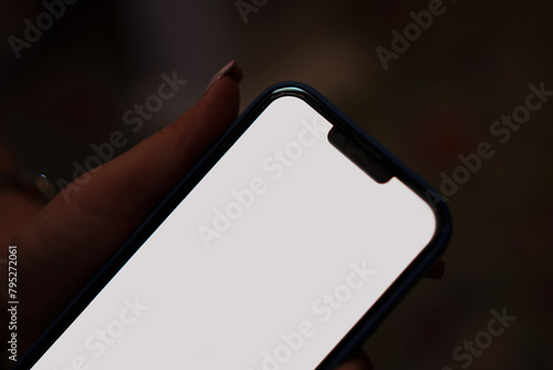 close-up. Smartphone with white screen in female hand on dark background. 