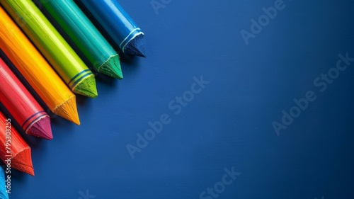 Vibrant colored pencils on blue background, sharp tips aligned diagonally, space for text.