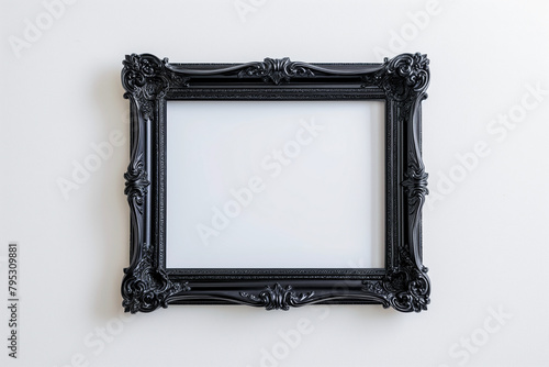 An ornate black picture frame with intricate designs, mounted on a white wall, empty and ready for artwork.