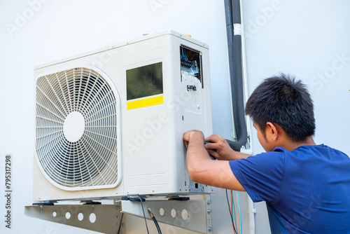 Male technician installing outdoor unit of air conditioner  to cool the household in the summer. air compressor, electronic, hot summer, high temperature, Tropical countries