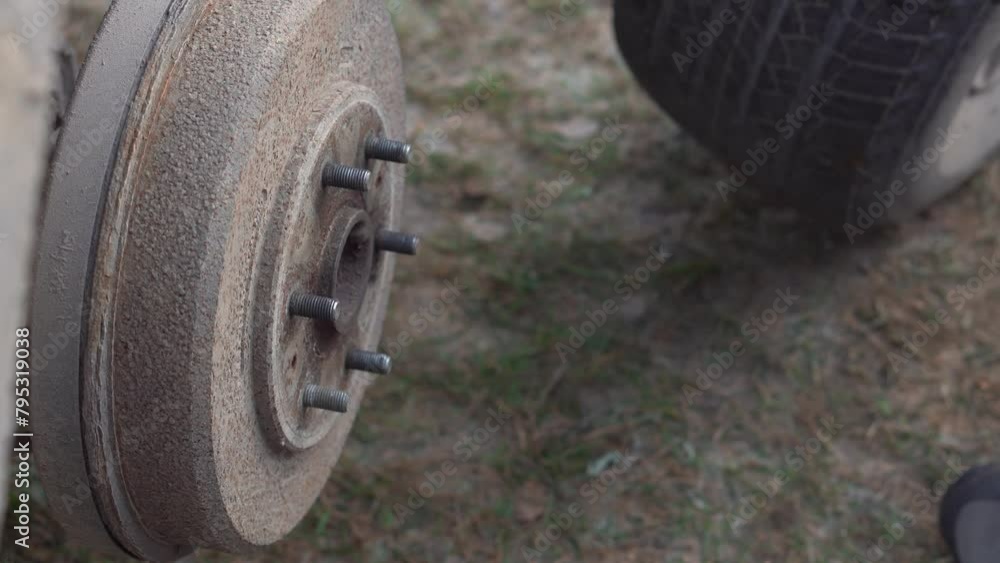 Man unscrews the wheel nuts for replacement with a wrench. Seasonal change of car tires. Man unscrews the wheel nuts for replacement with a wrench. Seasonal change of car tires.