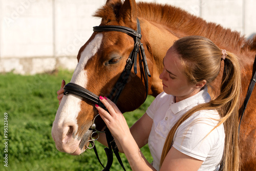 Woman attaching bridle to horse
