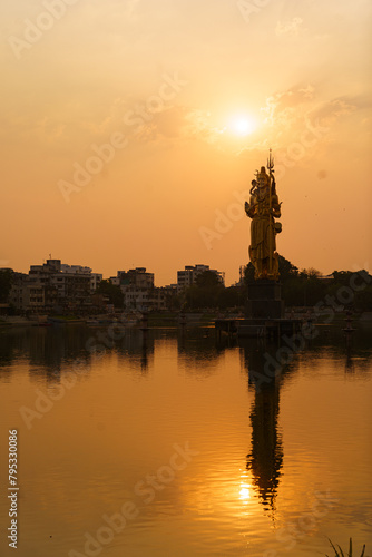 The Statue of Hindu god Lord Shiva in Sursagar Lake is seen at sunset in Vadodara city in the state of Gujarat. Concept of hinduism religion © davide bonaldo