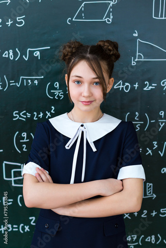 A girl advertises school clothes near a school board, the concept of a variety clothes for a school-age girl.